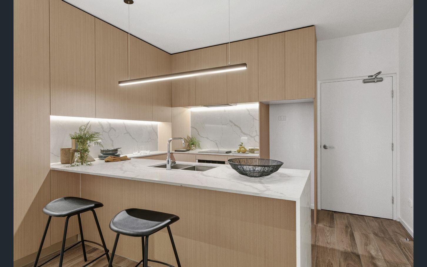 a modern kitchen with breakfast bar, led strip lighting and panelled wood cabinets